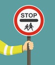 Hand holding school warden sign. United Kingdom road sign.