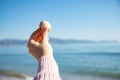 Hand holding a sea shell with the blurred see on the background Royalty Free Stock Photo