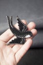 Hand holding seed bead embroidered brooch in a shape of black swallow bird