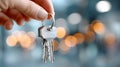 Hand holding a set of keys with a blurred background of warm lights, symbolizing access, security, and new beginnings in Royalty Free Stock Photo