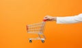 hand holding shopping cart on orange background Royalty Free Stock Photo