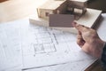 A hand holding and showing an empty business card with an architecture model and shop drawing paper on table