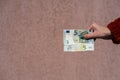 Hand holding showing euro money and giving or receiving money like tips, salary. 5 EURO banknotes EUR currency . Concept