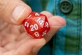 Hand holding a 20-sided d20 dice for RPG gaming, fingers closeup detail, one person, role-playing games, larp live action roleplay