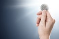 Hand holding a silver Ethereum coin on a gently lit background with copy space.