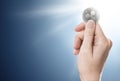 Hand holding a silver Ripple coin on a gently lit background