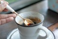 A hand holding silver spoon scooping some hot black coffee from a white ceramic mug Royalty Free Stock Photo