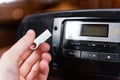 Hand holding silver USB flash drive connected to audio system or tape recorder. Royalty Free Stock Photo