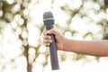 hand holding a single microphone against colourful background,singing contest. Royalty Free Stock Photo