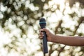 hand holding a single microphone against colourful background,singing contest. Royalty Free Stock Photo