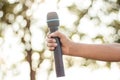 hand holding a single microphone against colourful background,singing contest. Royalty Free Stock Photo