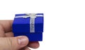 Hand holding small blue gift with silver ribbon Royalty Free Stock Photo