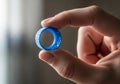 A hand holding a small blue plastic bottle cap between thumb and Royalty Free Stock Photo