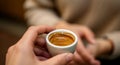 Hand holding small cup of fresh espresso with focus on creamy coffee surface Royalty Free Stock Photo