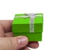 Hand holding small green collour gift with silver ribbon Royalty Free Stock Photo