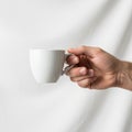 A hand is holding a small, plain white ceramic mug against a white Royalty Free Stock Photo