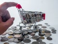 Hand holding small shopping cart with various currency coins using as shopping online or marketing concepts