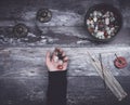 Hand holding small stones in energy healing meditation on rustic wooden table with burning incense and Tibetan prayer bells Royalty Free Stock Photo