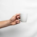A hand holding a small white ceramic mug against a plain white background Royalty Free Stock Photo