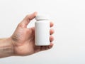 Hand holding a small white medicine bottle against a plain background Royalty Free Stock Photo