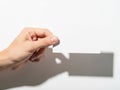 A hand holding a small white object in front of a white background with a shadow Royalty Free Stock Photo