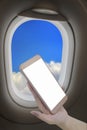 Hand holding smart phone with blank screen from airplane window Royalty Free Stock Photo