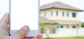 Hand holding smart phone with blank on screen over blurred house Royalty Free Stock Photo