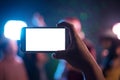 Hand holding smart phone with blank white screen. Photo shot blurry party and concert of event Background and copy space. Smart Royalty Free Stock Photo