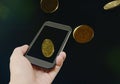 Hand holding smart phone and gold coin floating Royalty Free Stock Photo