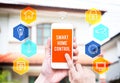 Hand holding smart phone with home control application with blur Royalty Free Stock Photo