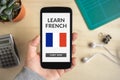 Hand holding smart phone with learn French concept on screen Royalty Free Stock Photo