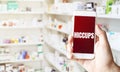 Hand holding smart phone in pharmacy drugstore. Text HICCUPS