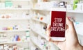 hand holding smart phone in pharmacy drugstore. Text STOP DRUNK DRIVING