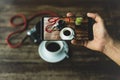 Hand holding smart phone taking photo of coffee and camera on wooden table. Royalty Free Stock Photo