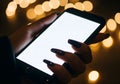 Hand holding smartphone with blank screen against bokeh lights Royalty Free Stock Photo