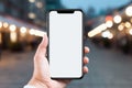 Hand holding smartphone with blank screen on blurred city background. Closeup of hand with cell phone screen mockup Royalty Free Stock Photo