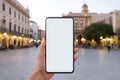 Hand holding smartphone with blank white screen mockup over European city old town background Royalty Free Stock Photo