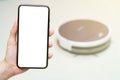 Hand holding smartphone with blanking screen for control robotic vacuum cleaner . Smart life technology concepts Royalty Free Stock Photo