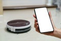 Hand holding smartphone with blanking screen for control robotic vacuum cleaner . Smart life technology concepts Royalty Free Stock Photo