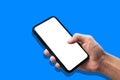 Hand holding smartphone on blue background. Royalty Free Stock Photo