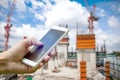 Hand holding smartphone on blurred construction site workers wit Royalty Free Stock Photo