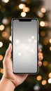 Hand holding smartphone with bokeh lights on background. Christmas concept Royalty Free Stock Photo
