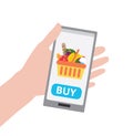 Hand holding smartphone with buy button and shopping basket full of healthy organic fresh and natural food Royalty Free Stock Photo
