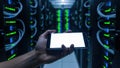Hand holding smartphone in data center server room with green lights glowing Royalty Free Stock Photo