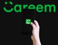 Hand holding smartphone displaying Careem app logo with blurred Careem text background illustrative Royalty Free Stock Photo