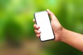 Hand holding a smartphone and an empty screen for your design on a natural green background in the morning concept. Mobile phone Royalty Free Stock Photo