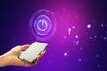 Hand holding smartphone with glowing power symbol on screen, digital interface, on a bokeh purple background, concept of Royalty Free Stock Photo