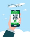 Hand holding Smartphone with Health Passport QR-code on the screen and airplane in sky.