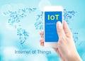 Hand holding smartphone with Internet of things (IoT) word at do