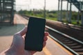 Hand holding a smartphone with railway station in the background